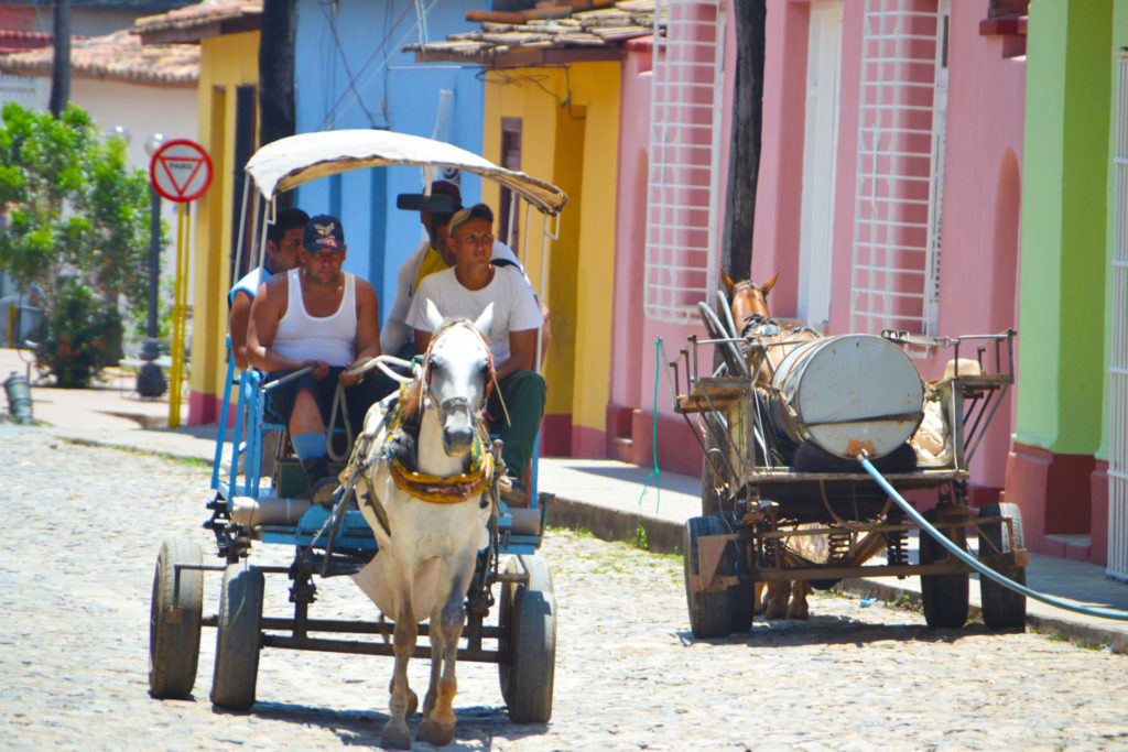Passengers in a horse drawn carriage along a cobblestone street in Trinidad